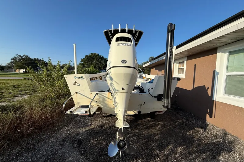 Slide: The Image of 1977 Mako 235 boat with outboard motor parked beside a house. - 4