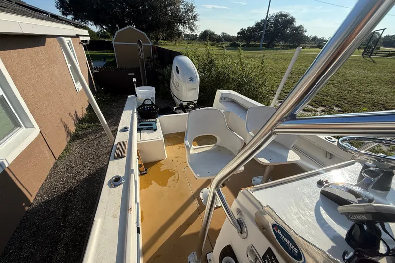 Slide: The Image of 1977 Mako 235 boat with seating and motor, parked outdoors near a house. - 18