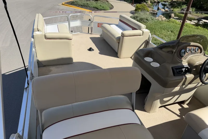 Slide: The Image of 1997 Sun Tracker Party Barge 21 Signature Series with beige seating and helm, docked outdoors. - 19