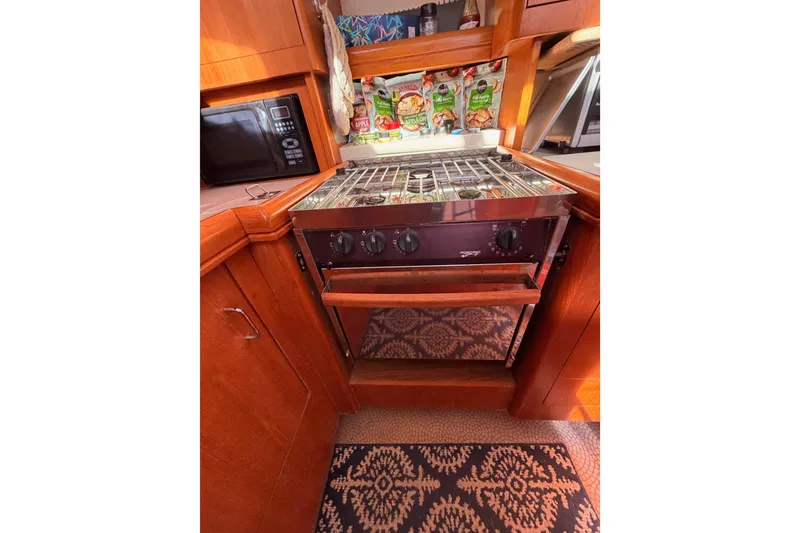 Slide: The Image of 2005 Hunter Passage 456 yacht kitchen with stove, microwave, and wooden cabinetry. - 40