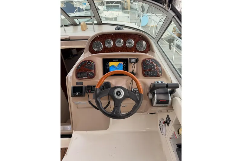 Slide: The Image of 2005 Sea Ray 300 Sundancer helm with steering wheel, gauges, and navigation controls. - 16