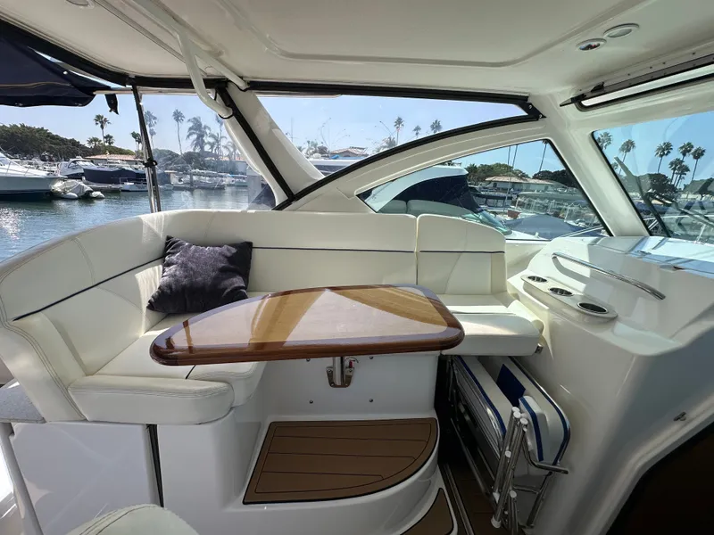 Slide: The Image of Interior of a 2007 Tiara Yachts 3000 Open with white cushioned seating and a wooden table. - 20