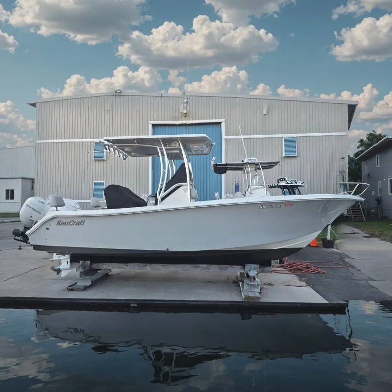 The Image of A 2024 KenCraft 215 Center Console boat is docked in front of a building. - 0