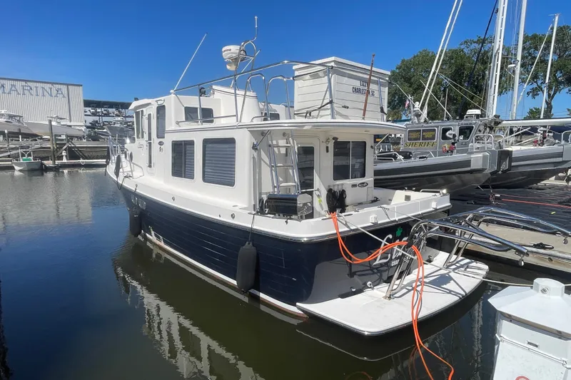 Slide: The Image of American Tug 34, 2003 model, docked at marina under clear blue sky. - 2