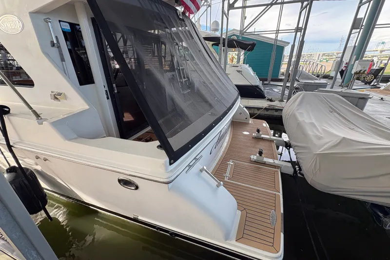 Slide: The Image of 2003 Symbol 50 Pilothouse yacht docked, featuring a spacious rear deck and protective canopy. - 5