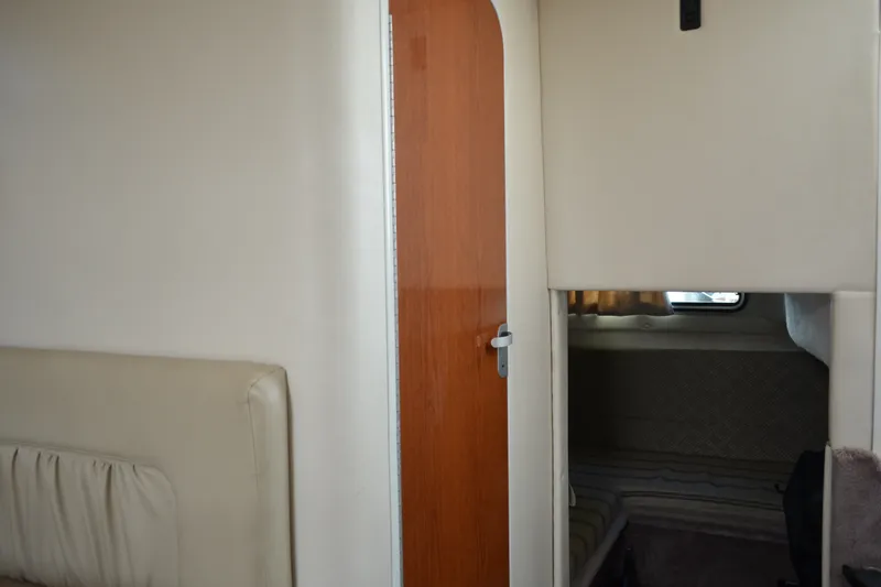 Slide: The Image of Interior cabin view of a 2001 Monterey 282 Cruiser boat, featuring a wooden door and cozy sleeping area. - 29