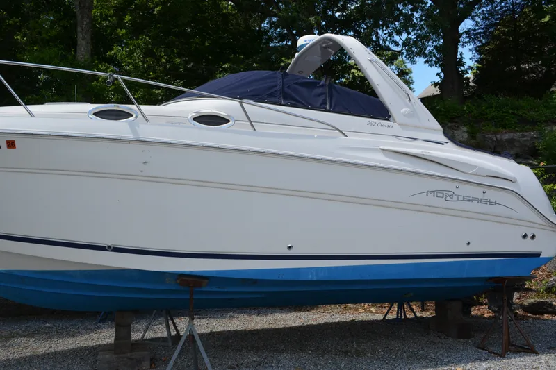 Slide: The Image of 2001 Monterey 282 Cruiser boat on stands, white hull with blue accents, outdoors. - 2