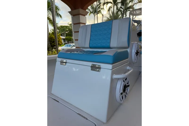 Slide: The Image of Blue and white boat seat on a 2025 V-Tech 18 model, surrounded by tropical plants. - 17