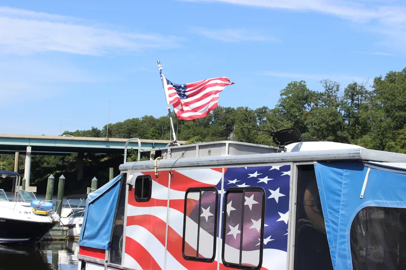 Slide: The Image of 1994 Sun Tracker Party Cruiser 32 with American flag design docked near a bridge. - 25