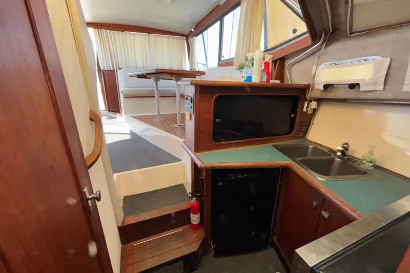 Slide: The Image of Interior of 1989 Bayliner 3288 Motoryacht featuring kitchen and dining area with wooden accents. - 17