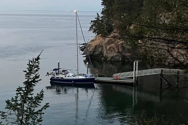 Slide: The Image of Sailboat Nauticat 37 (2002) docked in a serene, wooded coastal inlet. - 3