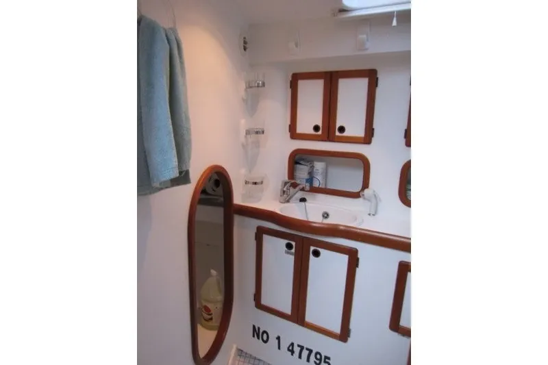 Slide: The Image of Nauticat 37 (2002) yacht bathroom with wooden cabinets and mirror. - 19