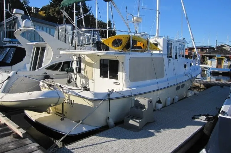 Slide: The Image of 2002 American Tug 34 docked, featuring a kayak on the roof and inflatable dinghy. - 25