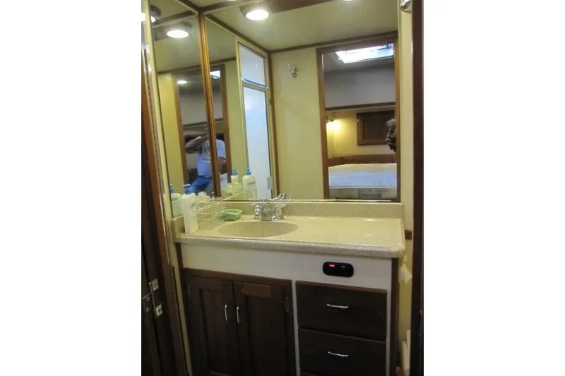 Slide: The Image of Bathroom vanity in 2002 American Tug 34, featuring mirror, sink, and storage cabinets. - 15