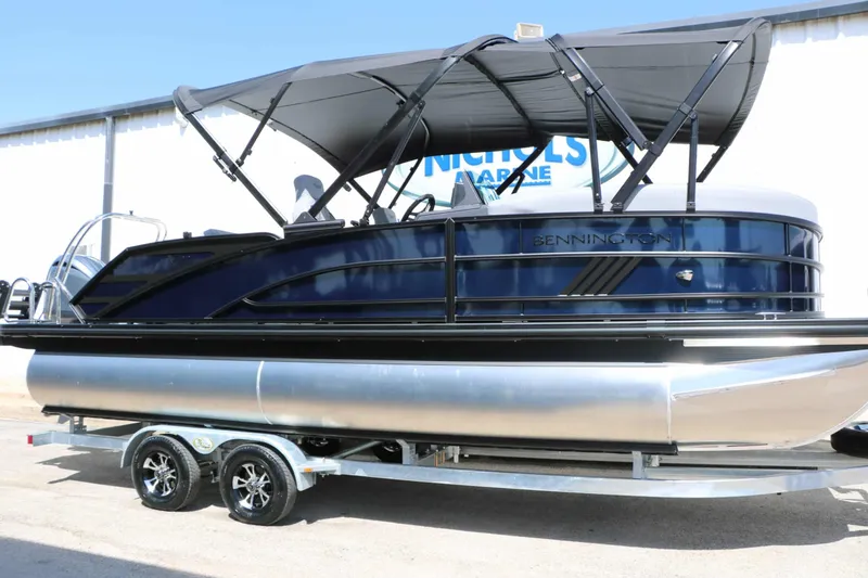 The Image of A 2027 Bennington 22 MSB Tri Toon on a trailer, featuring a black canopy. - 1