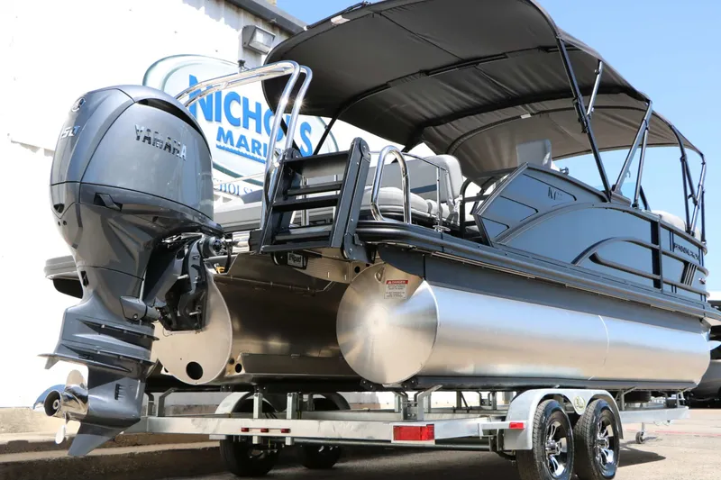 Slide: The Image of A modern 2027 Bennington 22 MSB Tri Toon on a trailer, featuring a large outboard motor. - 18