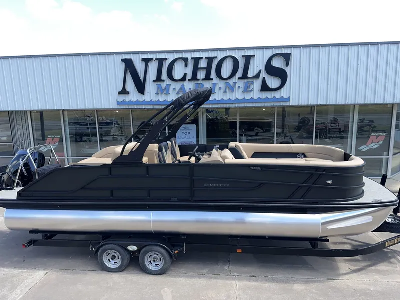 The Image of A 2027 Evotti 525 CS pontoon boat on a trailer in front of a building. - 1