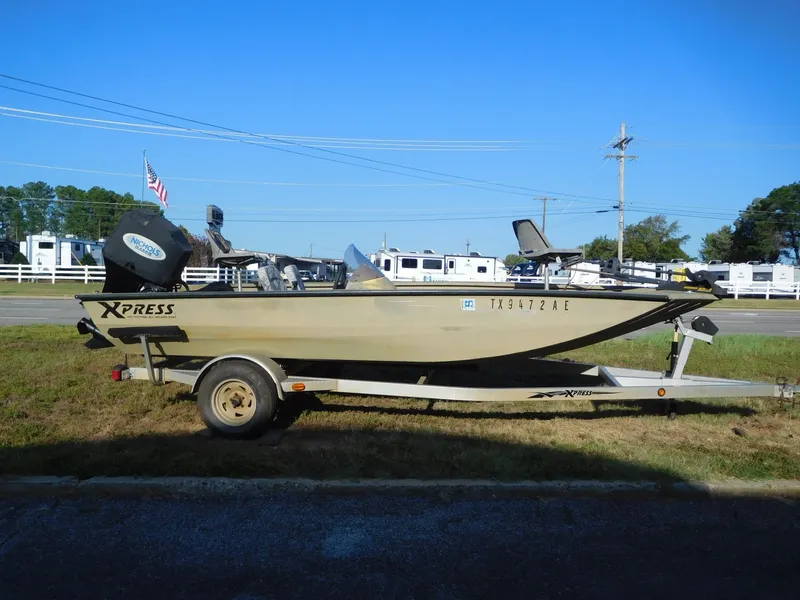 The Image of A 2006 Xpress HD 18 SC boat on a trailer, parked on grassy ground. - 1