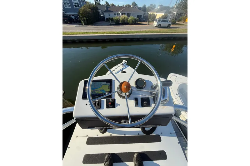 Slide: The Image of Steering console of a 2015 C-Hawk 25 Center Console boat by the water. - 8