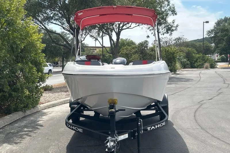 Slide: The Image of 2027 Tahoe T18 boat with red canopy on trailer, parked outdoors. - 4