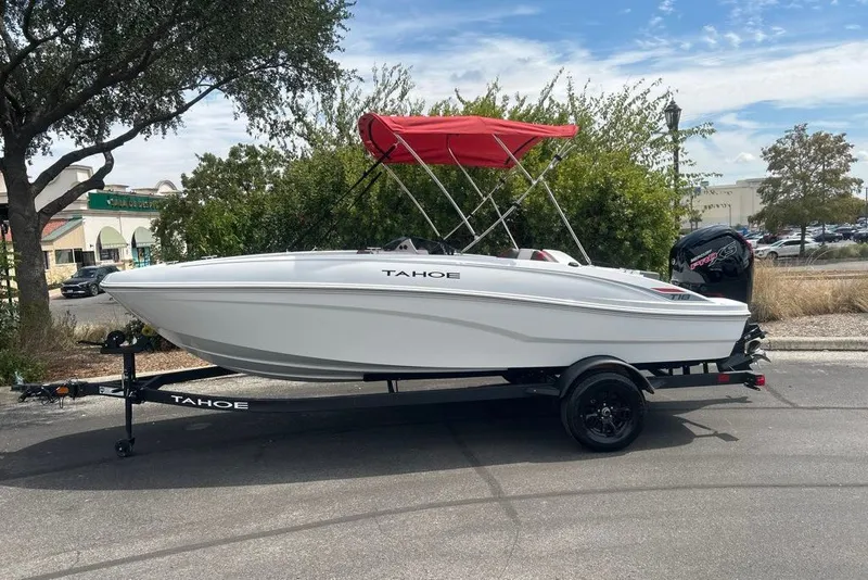 Slide: The Image of 2027 Tahoe T18 boat with red canopy on trailer, parked outdoors. - 1