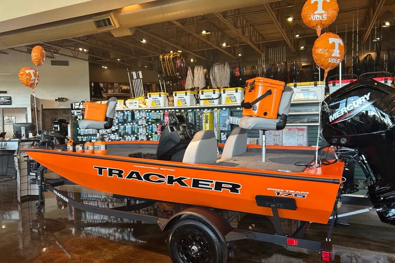 Slide: The Image of 2027 Tracker Pro Team 175 boat displayed in a showroom with fishing gear. - 38
