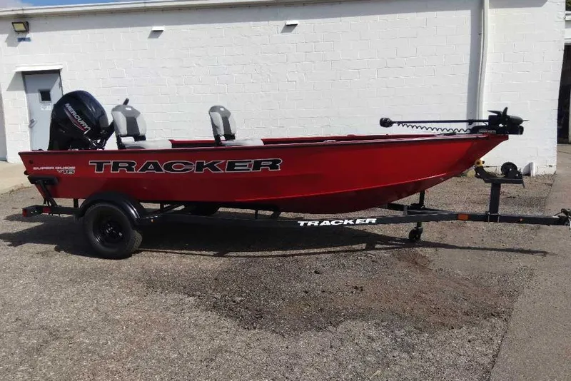 The Image of Red 2027 Tracker Super Guide V-16 T boat on trailer, parked outdoors. - 0