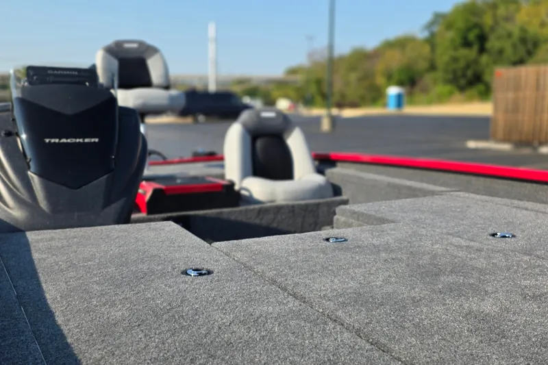 Slide: The Image of 2027 Tracker Savage 215 boat interior with seats and motor in a parking lot. - 13