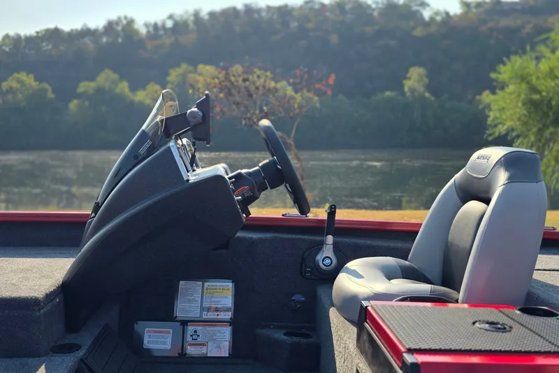 Slide: The Image of Interior of 2027 Tracker Savage 215 boat with steering wheel and seat by a lake. - 19