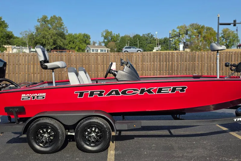 The Image of Red 2027 Tracker Savage 215 boat on trailer, parked outdoors with trees in background. - 0
