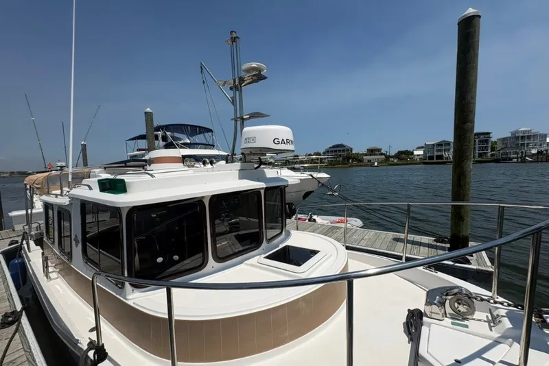 Slide: The Image of 2017 Ranger Tugs R-27 docked at marina, featuring Garmin equipment and scenic waterfront view. - 16