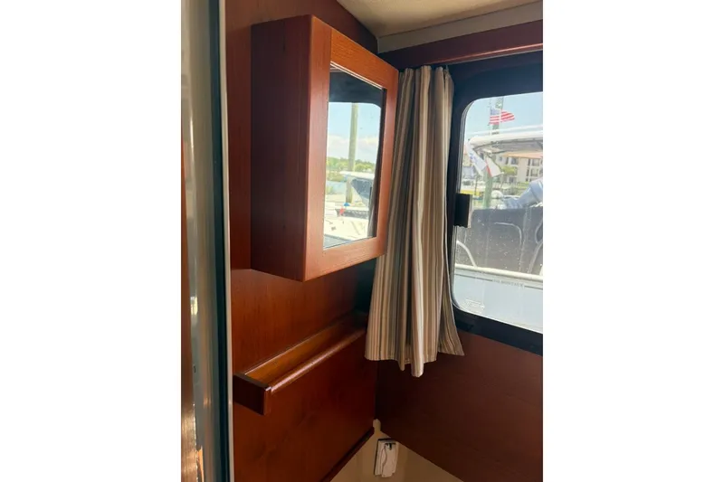 Slide: The Image of Interior of 2017 Ranger Tugs R-27 with wooden cabinetry and window curtains. - 53