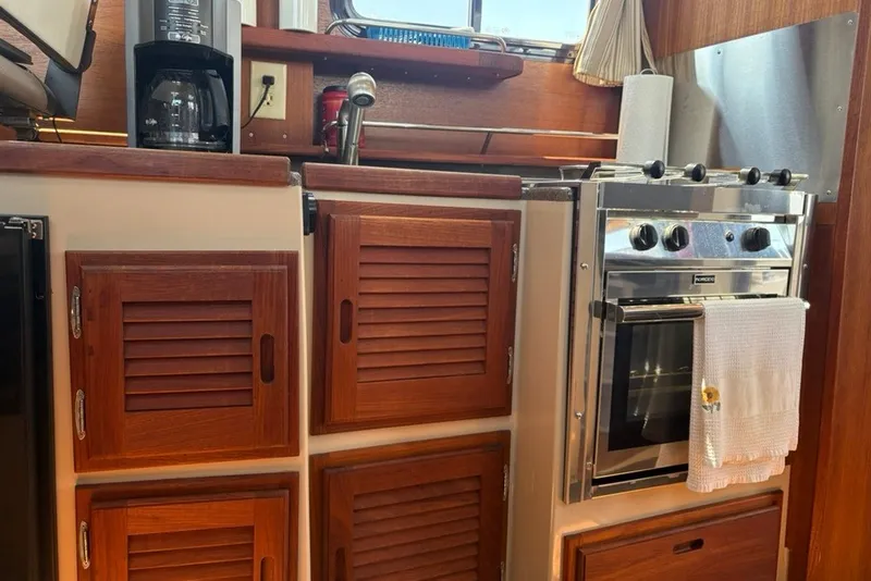 Slide: The Image of Cozy kitchen area in a 2017 Ranger Tugs R-27 boat with wooden cabinets and stove. - 50
