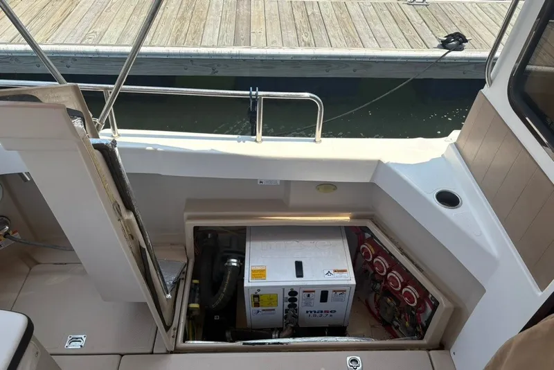 Slide: The Image of 2017 Ranger Tugs R-27 boat showing open engine compartment with generator near dock. - 69