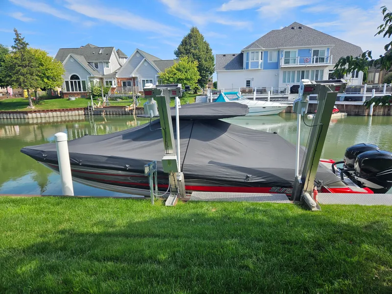 Slide: The Image of A 2017 Sunsation 32 CCX is docked in a serene residential canal, covered and on a boat lift. - 16