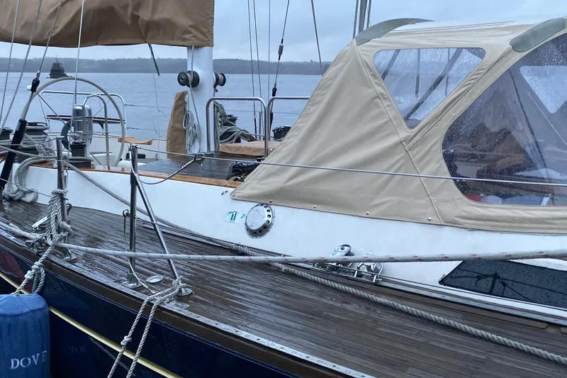 Slide: The Image of 1984 Ta Shing Skye 54 sailboat with beige canopy docked on a rainy day. - 5