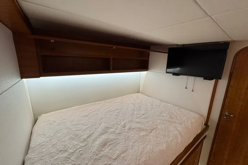 Slide: The Image of Cozy cabin interior of 2001 Southern Composite Sportfish with bed, TV, and wooden storage. - 20