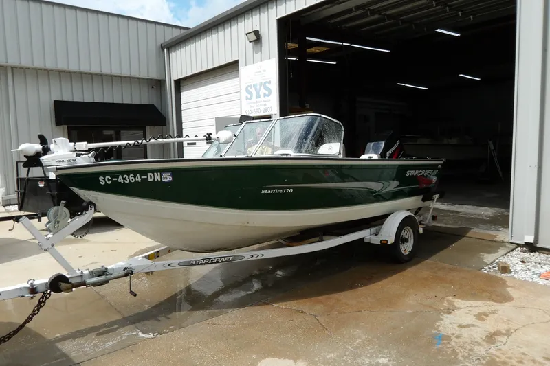 The Image of 2000 Starcraft C-Star 170 DC boat on trailer outside a garage. - 1