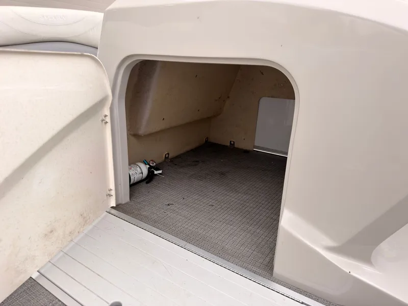 Slide: The Image of An open storage compartment on a 2017 Sylvan MIRAGE 8524 DL boat with gray carpet flooring. - 23