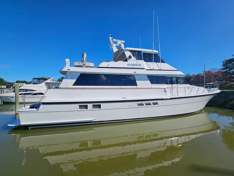 Slide: The Image of A white 1991 Hatteras 70 Cockpit Motor Yacht docked in calm waters. - 5