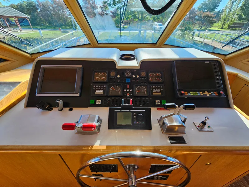 Slide: The Image of The image shows the helm of a 1991 Hatteras 70 Cockpit Motor Yacht with modern instruments. - 13