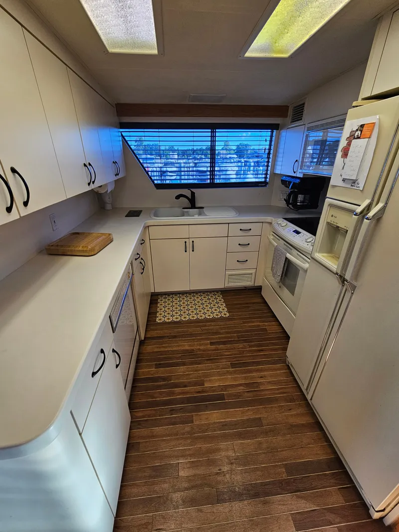 Slide: The Image of The 1991 Hatteras 70 Cockpit Motor Yacht's kitchen is spacious with white cabinets and wood flooring. - 14