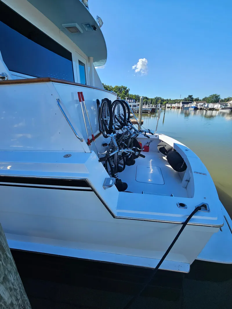 Slide: The Image of A 1991 Hatteras 70 Cockpit Motor Yacht docked. Bicycles are mounted at the stern. - 10