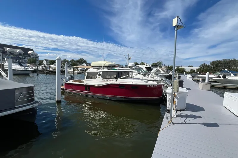The Image of 2022 Ranger Tugs R-27 docked at marina under blue sky. - 0