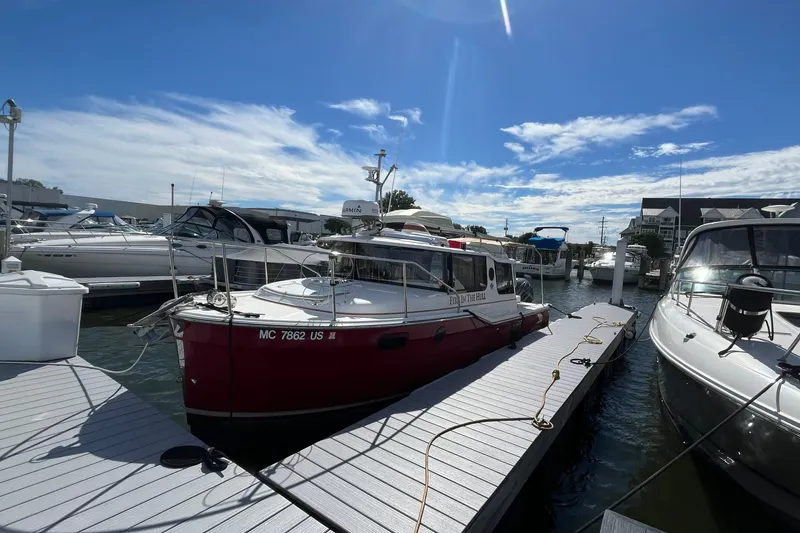 Slide: The Image of 2022 Ranger Tugs R-27 docked at marina under clear blue sky. - 1
