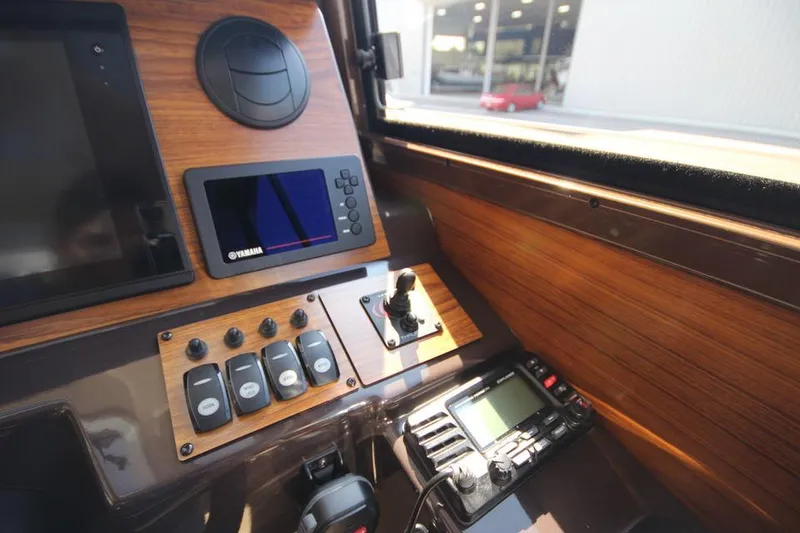 Slide: The Image of Das Bild zeigt das Armaturenbrett eines Ranger Tugs R-27 von 2022 mit Holzverkleidung und elektronischen Geräten. - 41