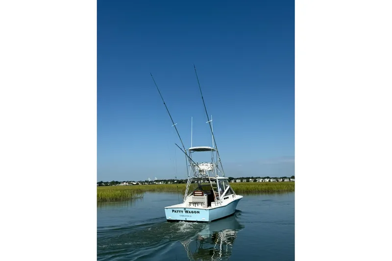 Slide: The Image of 1996 Carolina Classic 28 boat cruising on calm water under clear blue sky. - 15