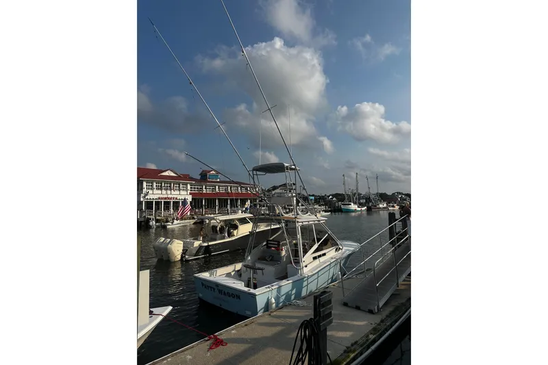 Slide: The Image of 1996 Carolina Classic 28 boat docked at a marina under a partly cloudy sky. - 8