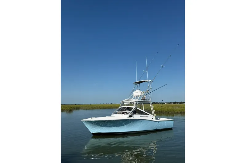 Slide: The Image of 1996 Carolina Classic 28 boat on calm water under clear blue sky. - 18