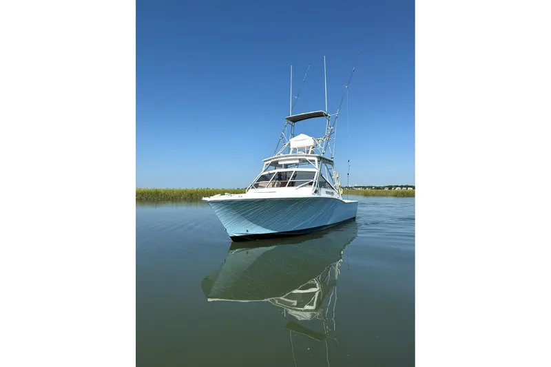 Slide: The Image of 1996 Carolina Classic 28 boat on calm water under clear blue sky. - 16